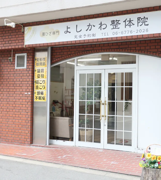 よしかわ整体院の外観。玉造の路面1階、ガラス張りの入口から院内の待合が見える